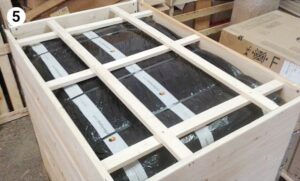 wooden crate with internal support beams securing black-wrapped package