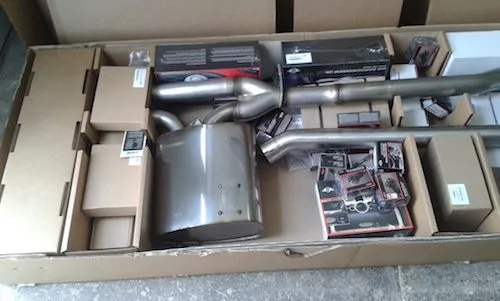 metal automotive exhaust components neatly arranged inside large shipping box